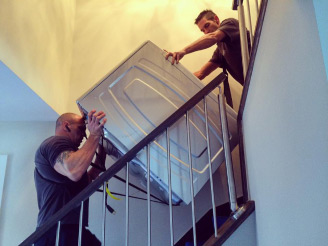déménageurs de Déménagement AR Masson en train de descendre une sécheuse dans une cage d’escalier